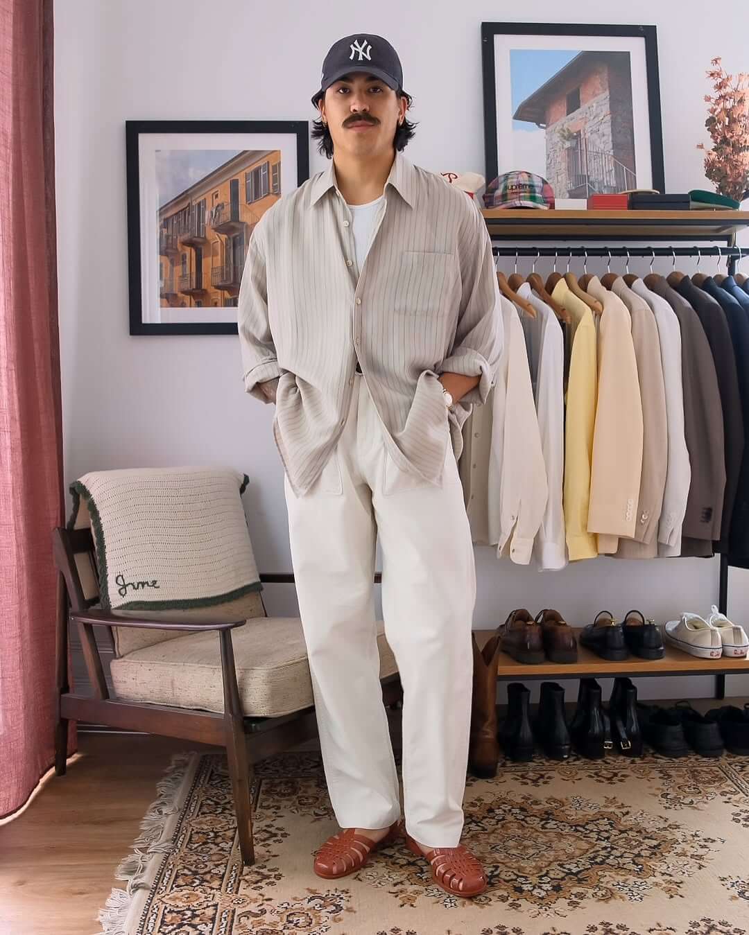 stylish man wearing an oversized striped shirt over a white tank top with white jeans and brown leather fisherman sandals